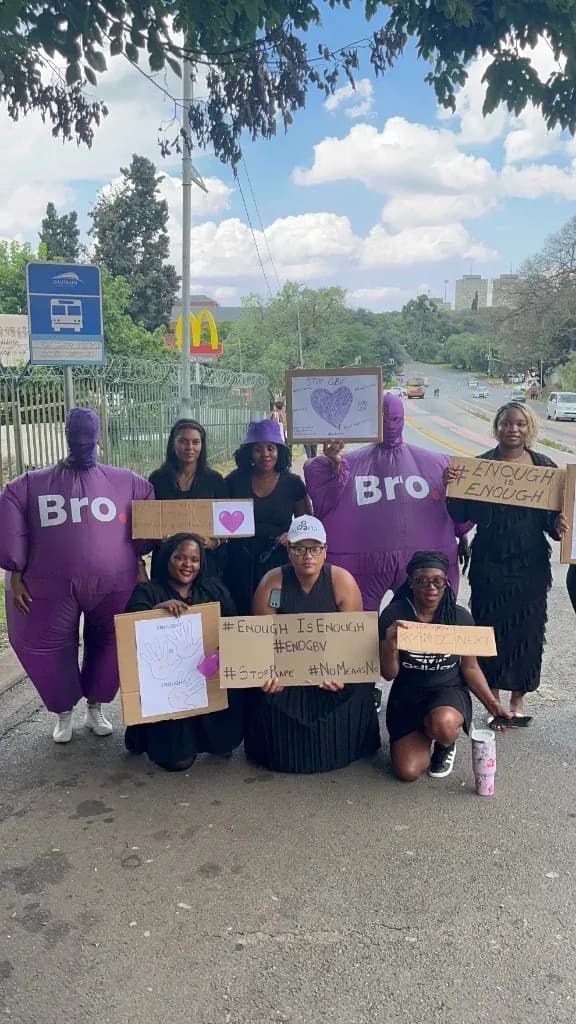 Community members and Bro mascots holding Enough Is Enough and Stop GBV signs